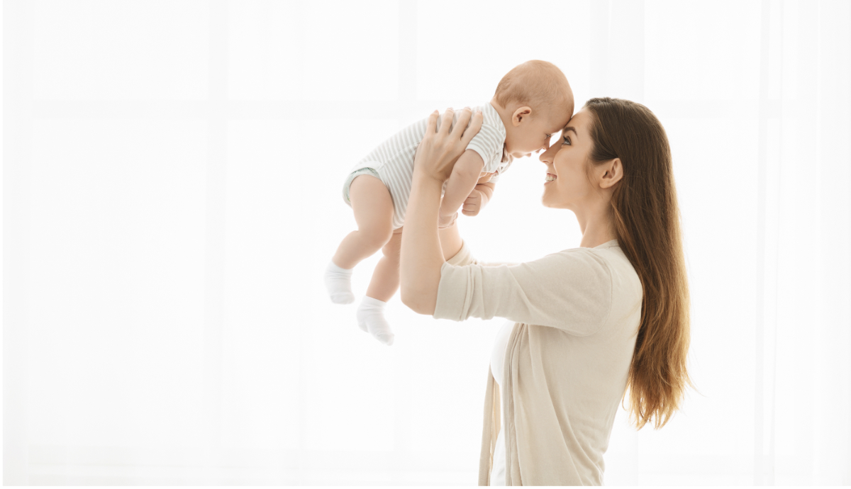Smiling mother lifting baby in the air after resolving breastfeeding challenges